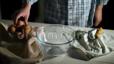 男人的手在碗里打碎鸡蛋。 厨师用玻璃碗打碎鸡蛋